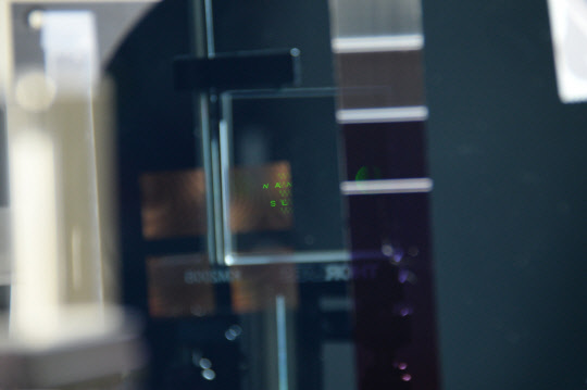 ETRI가 상전이 물질을 이용해 1마이크로미터 크기의 픽셀을 만들어 제작한 홀로그램 동영상(나노 슬림)의 모습으로, 스마트폰의 손전등(LED)를 비추자 '나노 슬림'이라는 녹색 글씨의 홀로그램이 보인다.  ETRI 제공